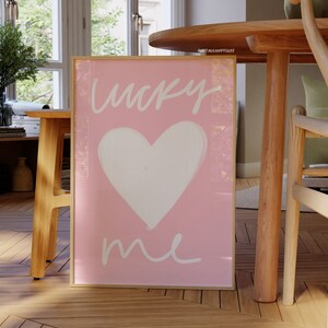 May include: A pink framed print with a white heart and the text "lucky me" in white script.