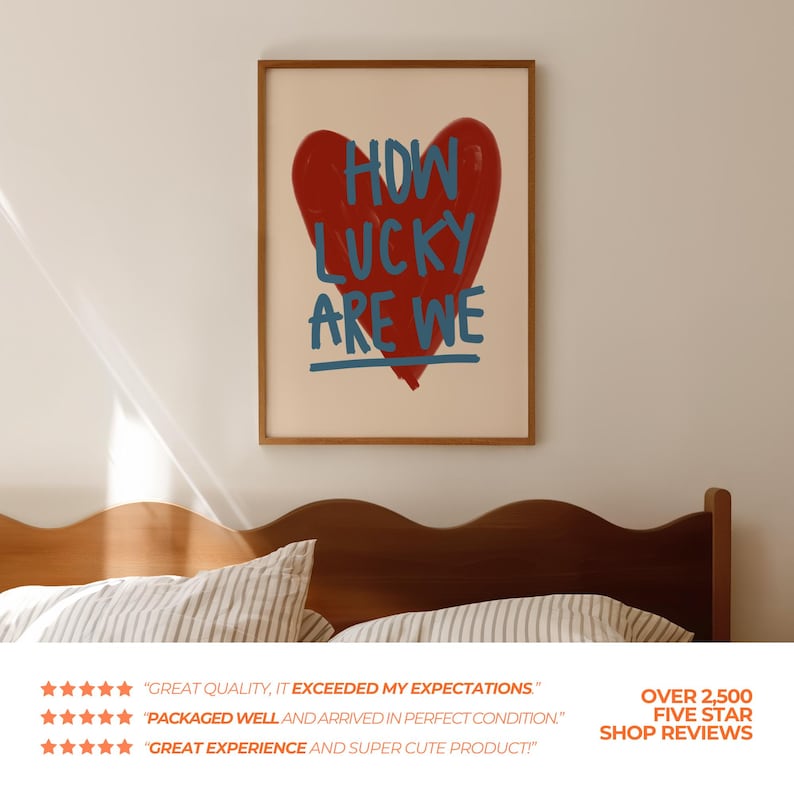 May include: A framed art print featuring a large red heart with the words "HOW LUCKY ARE WE" in blue. The artwork is displayed above a wooden headboard. The print has a cream-colored background and a wooden frame.