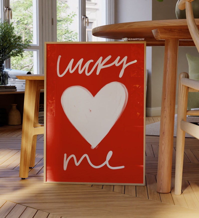 May include: A framed red canvas print with white lettering that says "lucky me" and a white heart shape in the center.