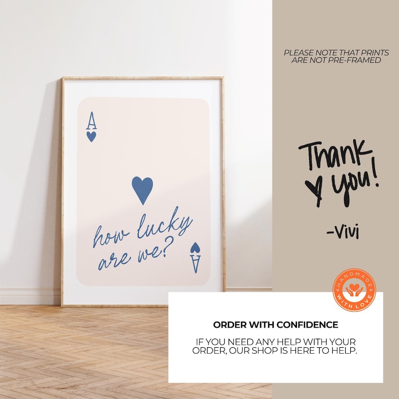 Pu&ograve; includere: Una stampa d'arte stampabile con uno sfondo rosa e un design di carta da gioco di asso di cuori blu. La carta dice "how lucky are we?" in scrittura nera. La stampa &egrave; incorniciata in una cornice di legno chiaro.