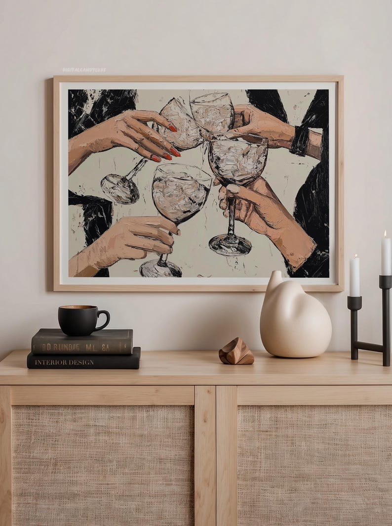 May include: A framed painting of four hands holding up glasses of wine, with a white background and black accents. The painting is hanging on a wall above a wooden shelf with books and decorative objects.