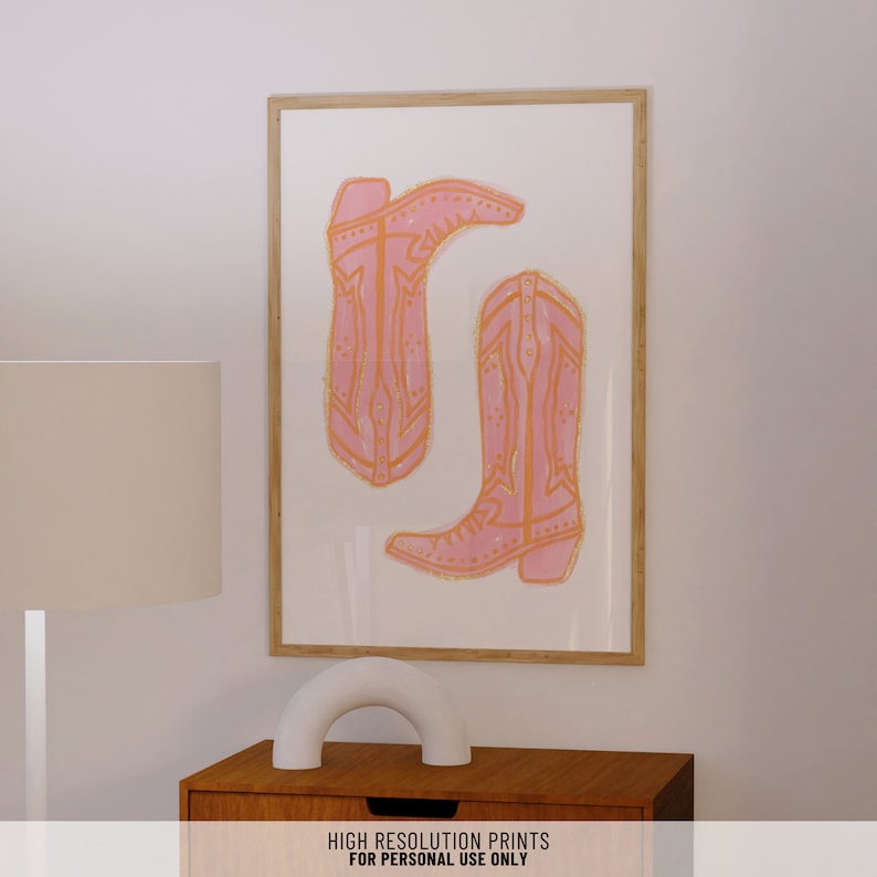 Puede incluir: Una impresi&oacute;n enmarcada de dos botas de vaquero rosas con costuras naranjas. Las botas est&aacute;n dibujadas de forma simple y estilizada. La impresi&oacute;n est&aacute; sobre un fondo blanco.