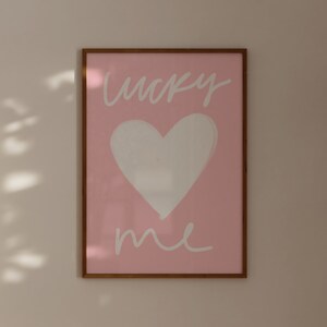 May include: A framed pink print with a white heart and the text "lucky me" in white cursive.