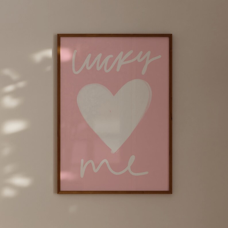 May include: A framed pink print with a white heart and the text "lucky me" in white cursive.