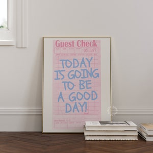 May include: A pink and white guest check with the text "TODAY IS GOING TO BE A GOOD DAY!" written in blue. The check has a grid pattern and the words "Guest Check" are printed at the top.