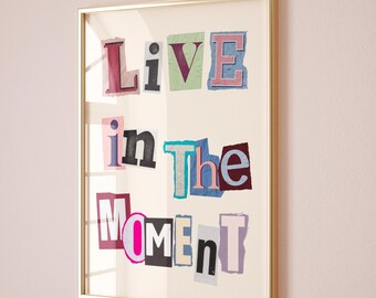 May include: A framed print with the words "Live in the Moment" in colorful, cut-out letters. The letters are arranged in a staggered pattern, creating a visually appealing and inspiring message.