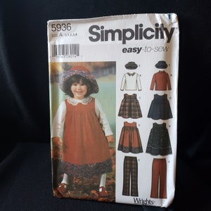 May include: Simplicity sewing pattern number 5936, easy-to-sew, for sizes M 1, 2, 3, 4. The pattern includes instructions for making a dress, a hat, a blouse, and pants. The dress is shown in a brown and red plaid fabric. The hat is a brown and white sun hat. The blouse is a white long-sleeved blouse. The pants are brown and red plaid pants.