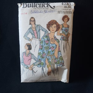 May include: A vintage sewing pattern for a women's top and blouse. The pattern is from the Butterick brand and is size 14. The pattern features three different styles of tops, including a floral print top, a striped top, and a solid color top.