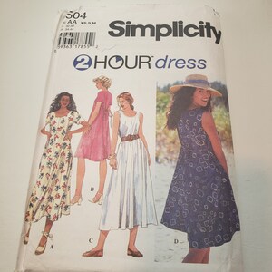 Könnte beinhalten: Simplicity Schnittmuster Nummer 504 für ein 2-Stunden-Kleid. Das Schnittmuster umfasst vier verschiedene Stile: ein Kleid mit Blumendruck und kurzen Ärmeln, ein rosa Kleid mit einer Schleife im Rücken, ein weißes Kleid mit einem Gürtel und ein blaues Kleid mit geometrischem Muster.