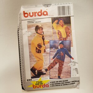 May include: A sewing pattern for children's clothing from Burda. The pattern includes instructions for a yellow jacket with brown patterned sleeves, yellow pants, a blue sweater with a brown graphic, and blue pants with a brown patterned design. The pattern is for sizes 110, 116, 122, and 128.