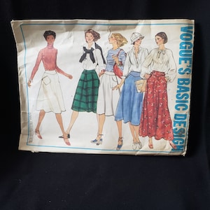 May include: Vintage Vogue's Basic Design sewing pattern. The pattern features illustrations of five different outfits, including skirts, blouses, and a striped top. The cover is off-white with the text "Vogue's Basic Design" in blue.