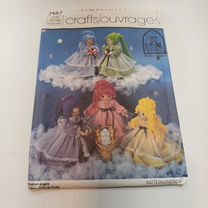 May include: A vintage Simplicity sewing pattern for making gingham angels. The pattern number is 7187 and the title is "crafts/ouvrages". The pattern includes instructions for making four different angels, each with a different color dress and hair. The pattern also includes a small illustration of a castle.