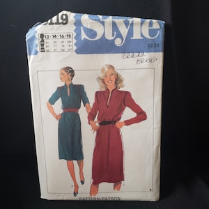 May include: Vintage sewing pattern featuring illustrations of two dresses. The pattern packet is primarily blue and white, with the word "Style" prominently displayed. The illustrations depict a teal and a burgundy dress with black trim and belts. The pattern is for sizes 12-18.