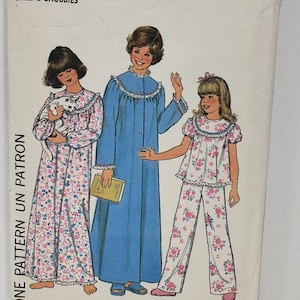 Op de afbeelding: Simplicity naaipatroon nummer 8127 voor kleine meisjes en mollige meisjes. Het patroon bevat drie verschillende stijlen pyjama's: een nachtjapon met lange mouwen met een bloemenprint, een nachtjapon met lange mouwen in effen blauwe kleur en een set met een top met korte mouwen en broek met een bloemenprint.