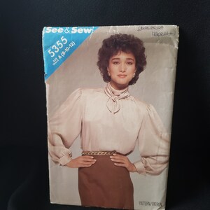 Op de afbeelding: Een vintage naaipatroon getiteld "See & Sew 5355" met een vrouw in een lichtroze blouse met een stropdas en een bruine rok. De patroonmaat is A (8-10-12). De afbeelding heeft handgeschreven notities.