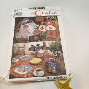 May include: Simplicity Crafts pattern number 8213, a vintage sewing pattern for making Christmas-themed home decor. The pattern includes instructions for making a table runner, pot holders, oven mitts, and gift bags. The pattern cover features a colorful illustration of the finished projects.
