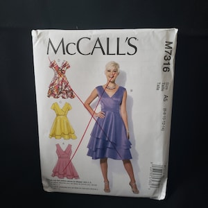 May include: A McCall's dressmaking pattern, showing illustrations of three dress styles. The white pattern envelope displays the McCall's logo and pattern number M7316. The size is A5, fitting sizes 6-8-10-12-14.
