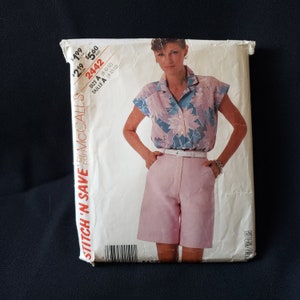 May include: A sewing pattern for a women's blouse and shorts. The pattern is from McCall's Stitch 'n Save line and is size A (8-10-12). The blouse has a floral print and the shorts are pink.