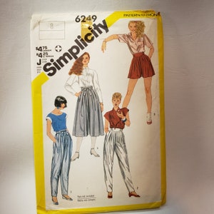 May include: Simplicity sewing pattern number 6249, featuring three different styles of pants. The pattern includes instructions for making high-waisted pants with a wide leg, a pair of cuffed pants, and a pair of culottes. The pattern is for sizes J.