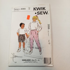 May include: Sewing pattern for children's clothing, Kwik Sew pattern number 2055, sizes 4-5-6-7, includes a white shirt and pink pants with a floral print.