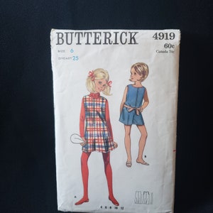 Może przedstawiać: Wzorzec szycia vintage dla sukienki dla dziewczynki, z sukienką w kratę z golfem i sukienką z denimowym fartuchem. Wzorzec pochodzi od Butterick, rozmiar 6, a numer wzorca to 4919.