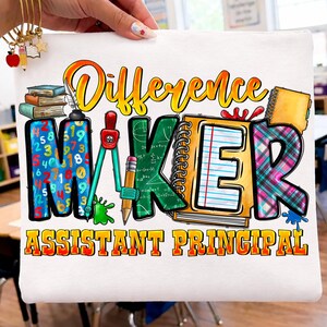 Peut inclure: Sac fourre-tout blanc avec l'inscription "Difference Maker Assistant Principal" en orange et jaune. Le mot "MAKER" est orné de graphismes scolaires, dont un cahier, un compas et des livres. Le sac est tenu par une personne.