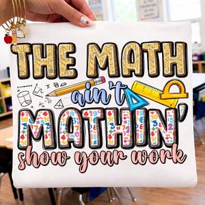 Könnte beinhalten: Weiße Canvas-Tragetasche mit dem Text "THE MATH ain't MATHIN' show your work" in einem farbenfrohen, verspielten Design. Mit mathematischen Symbolen, einem Bleistift, Lineal und Winkelmesser. Für Lehrer oder Schüler.