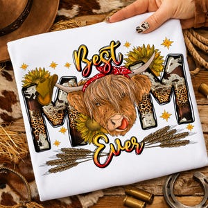 May include: White t-shirt with a graphic design featuring a Highland cow with a red bandana, sunflowers, and the text "Best Mom Ever." The letters "MOM" have a cowhide and leopard print pattern. A cowboy hat is also included.
