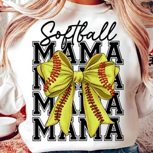 May include: White sweatshirt with the text "Softball Mama" in black script above a large yellow bow with red stitching, resembling a softball. The word "MAMA" is stacked four times in a bold, black font.