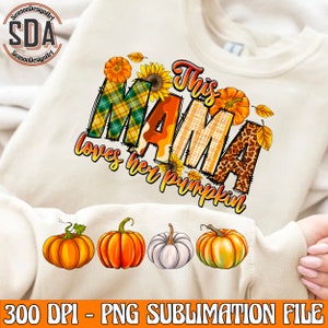May include: A sublimation design featuring the text "This Mama loves her pumpkin" in a patchwork style with fall colors and a sunflower. The design includes four pumpkins, two orange and one white.