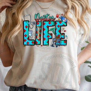 May include: A white t-shirt with the text "Doctor Life" in blue and red letters. The letters are decorated with medical symbols like a stethoscope, pills, and a wheelchair.