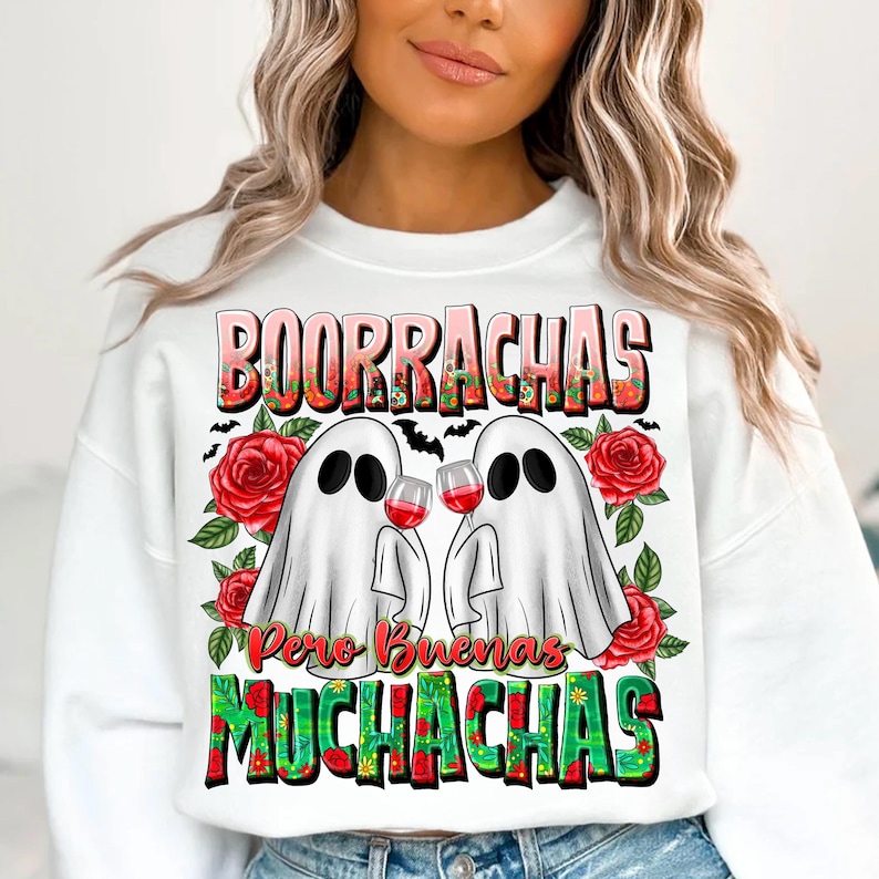 May include: White sweatshirt with a graphic featuring two ghost figures toasting wine glasses. The text "BOORRACHAS Pero Buenas MUCHACHAS" is displayed in a colorful, floral design, with red roses and bats.