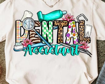 Op de afbeelding: Wit T-shirt met de tekst "Dental Assistant" in een kleurrijk ontwerp. Het woord "Dental" is uitgevoerd in een mix van patronen, waaronder luipaardprint en groene ruitjes. Tandheelkundige instrumenten, een tandenborstel en tandpasta zijn ook afgebeeld.