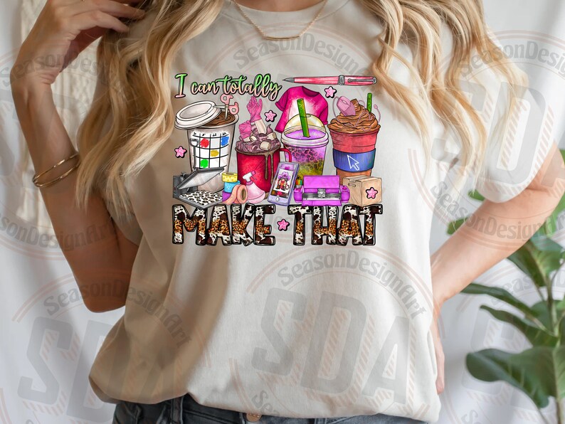 May include: A white t-shirt with the text "I can totally MAKE THAT" in black and brown lettering. The text is surrounded by a variety of colorful illustrations, including coffee cups, paintbrushes, and other craft supplies.