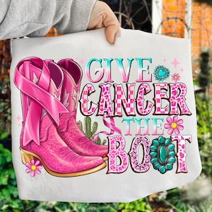 Könnte beinhalten: Eine weiße Tragetasche mit rosa Cowboystiefeln, einem rosa Band und dem Text "GIVE CANCER THE BOOT". Das Design umfasst florale und türkisfarbene Akzente sowie eine Kaktusillustration.
