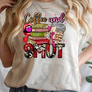 Op de afbeelding: Een wit T-shirt met de tekst "Coffee and Smut" in roze, rode en zwarte letters. De tekst wordt omringd door een stapel boeken met titels als "Forbidden Romance" en "Dark Romance". Een roze koffiebeker met een skelet hand die deze vasthoudt is ook afgebeeld.