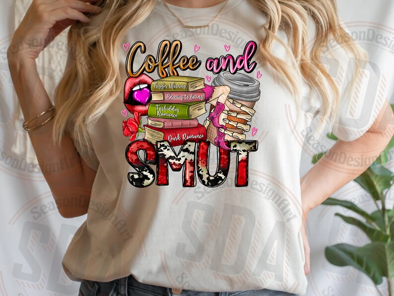 Op de afbeelding: Een wit T-shirt met de tekst "Coffee and Smut" in roze, rode en zwarte letters. De tekst wordt omringd door een stapel boeken met titels als "Forbidden Romance" en "Dark Romance". Een roze koffiebeker met een skelet hand die deze vasthoudt is ook afgebeeld.