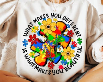 May include: White sweatshirt with a colorful puzzle piece design and the text "What makes you different is what makes you beautiful".