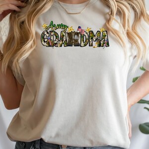 May include: A white t-shirt with a camouflage print design that says "Army Grandma" with a small American flag and stars.
