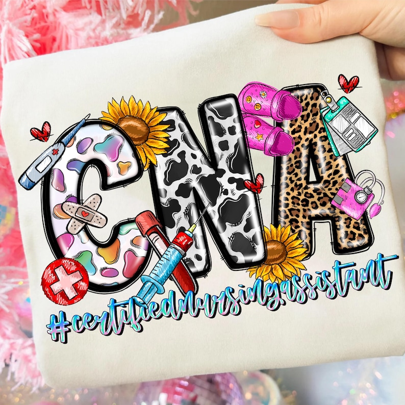 Peut inclure: Sweat-shirt cr&egrave;me avec les lettres "CNA" dans un design color&eacute;. Le "C" est d&eacute;cor&eacute; d'un motif arc-en-ciel, le "N" d'un imprim&eacute; vache et le "A" d'un imprim&eacute; l&eacute;opard. Le texte "#certifiednursingassistant" est en dessous.