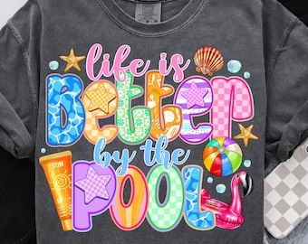 May include: A dark grey t-shirt with the text "Life is better by the pool" in colorful letters. The letters are decorated with a variety of summer-themed designs, including a seashell, a starfish, a flamingo, a beach ball, and a bottle of sunscreen.