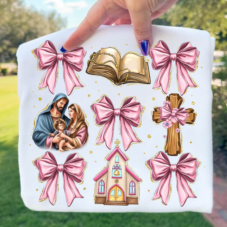 May include: White fabric featuring religious illustrations and pink bows with gold glitter accents. The images include a depiction of the Holy Family, a church, a cross, a rosary, and an open book.