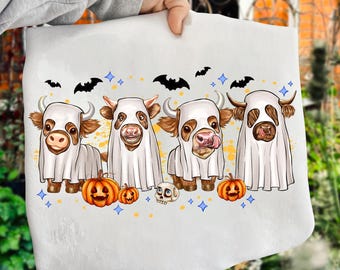 May include: A white Halloween-themed towel featuring four cartoon cows dressed as ghosts. The cows have brown and white markings, with orange pumpkins, a skull, and bats. Blue diamond shapes and bats are scattered around the cows.