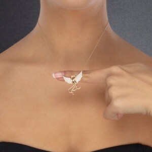 May include: A gold necklace with a detailed, sparkling, bird pendant. The bird has spread wings and a long tail.