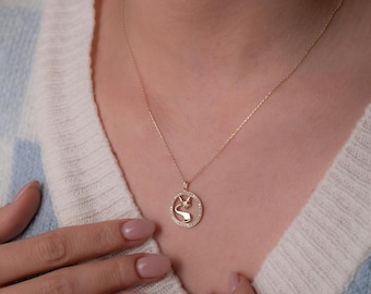 May include: A gold necklace with a pendant featuring a bird design surrounded by small clear stones.