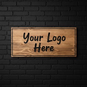 May include: Wooden sign with the text "Your Logo Here" in black, set against a light brown wood grain background. The sign has a black border and is mounted on a black brick wall.