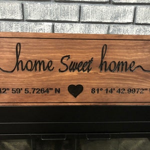 Peut inclure: Panneau en bois marron avec l'inscription "home Sweet home" en &eacute;criture cursive. Le panneau comporte &eacute;galement un c&oelig;ur noir et des coordonn&eacute;es : 42&deg; 59' 5.7264" N et 81&deg; 14' 42.9972" W. Forme rectangulaire.