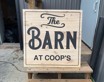 May include: A wooden sign with black lettering that reads "The Barn at Coop's".