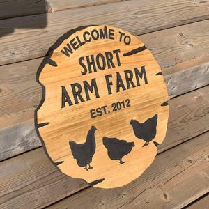 May include: A wooden sign with the text "Welcome to Short Arm Farm Est. 2012" and three black silhouettes of chickens.