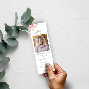 May include: A white memorial card with a pink floral design and a photo of a woman. The text "Celebrating the life of Michelle Smith" is printed on the card. The dates "January 12, 1982 - March 3, 2023" and the address "123 Anywhere Street, Any City, ST 12345" are also printed on the card.